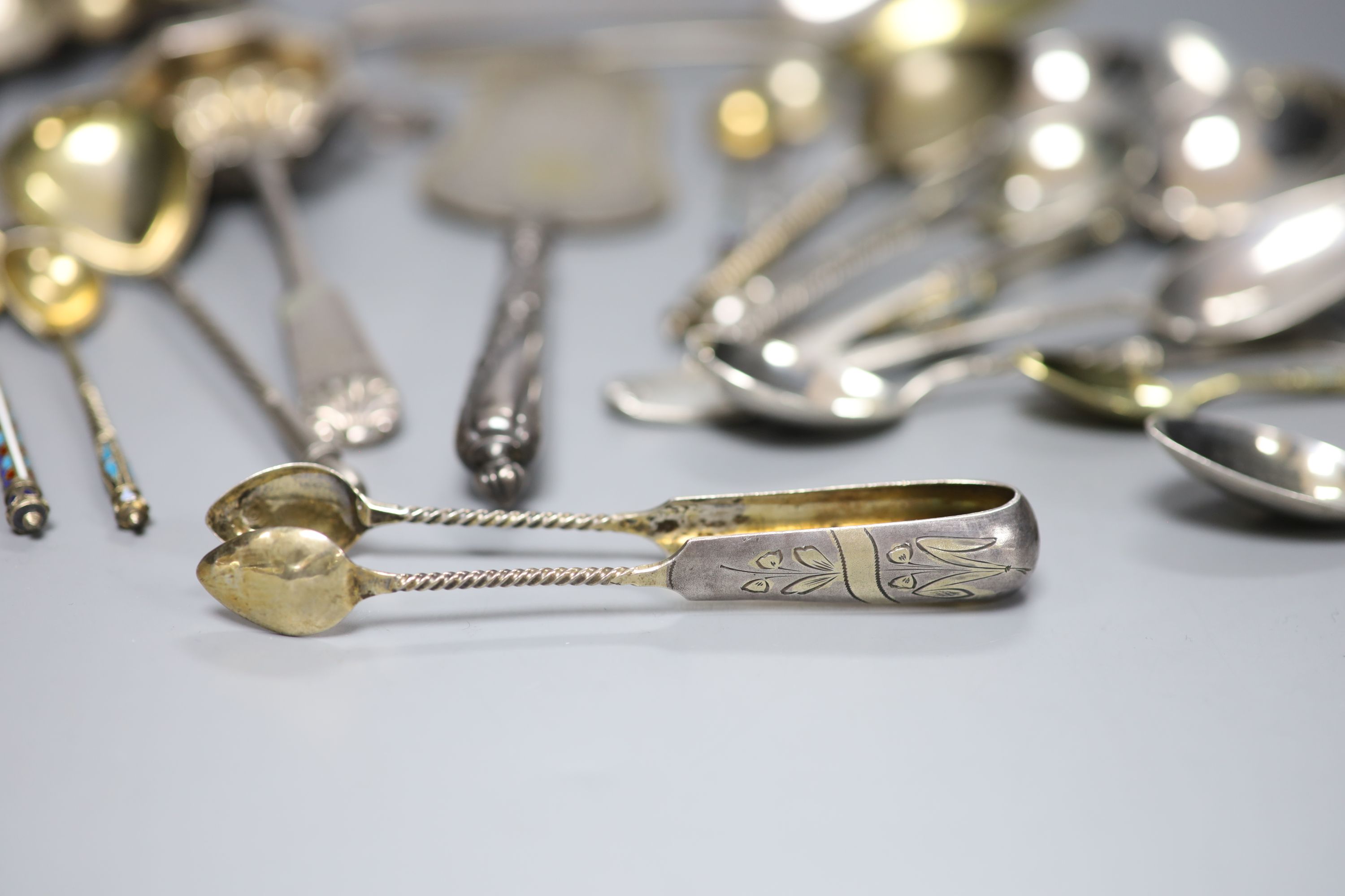 A late 19th century Russian 84 zolotnik tea strainer, a Russian cake slice and sugar sifter and a group of other Russian flatware including enamelled teaspoons